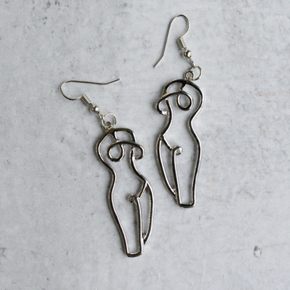Close-up-of-silver-drop-earrings-featuring-unique-woman-form-line-art-inspired-design